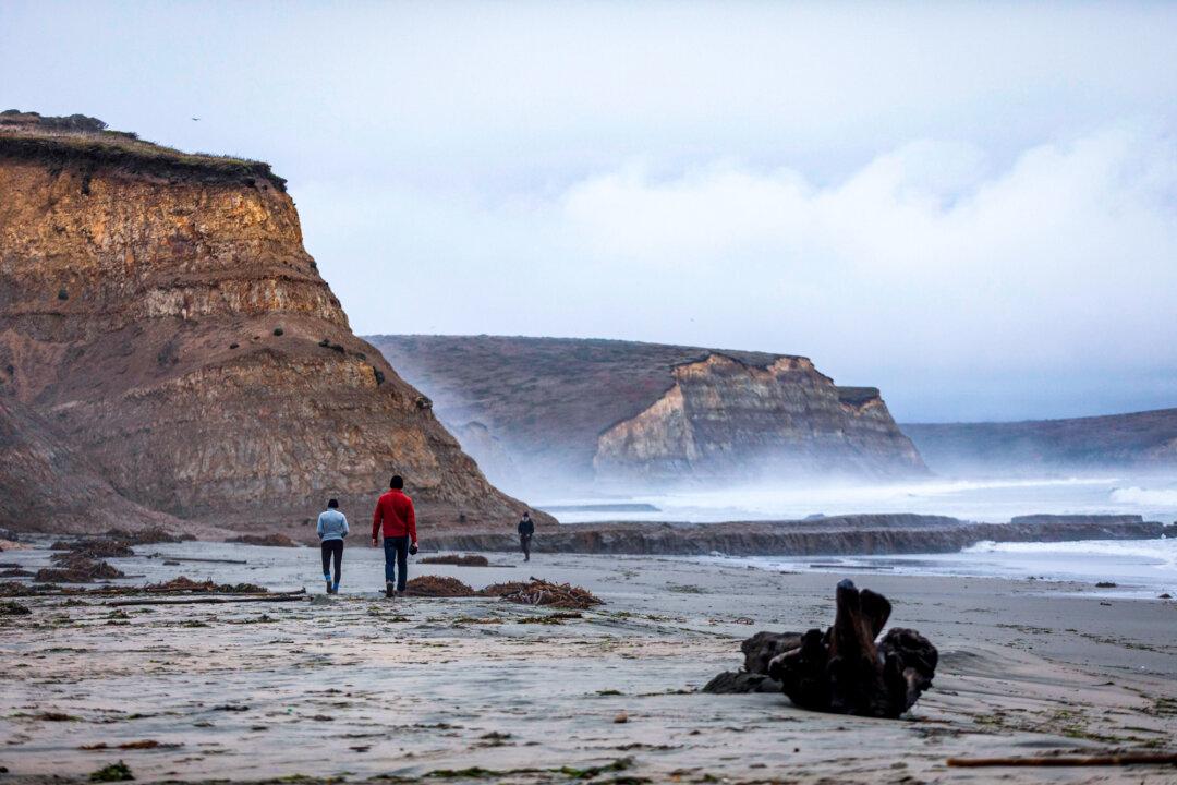 People walk along the coast as the fog rolls in at Drakes Beach in Inverness, Calif., on Dec. 13, 2019. (Philip Pacheco/AFP via Getty Images)