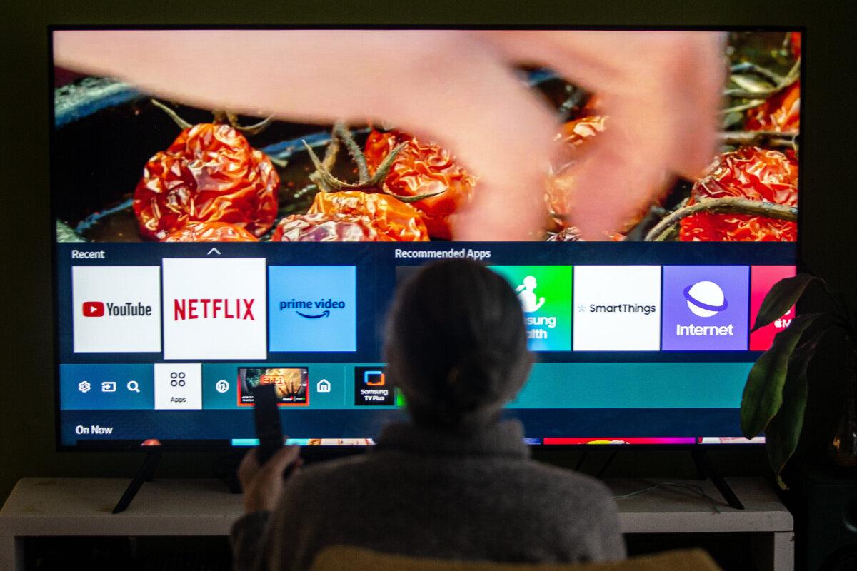 A person browses a television menu showing icons for streaming services Netflix and Amazon Prime, in this photo illustration made in Toronto on March 22, 2024. (The Canadian Press/Giordano Ciampini)