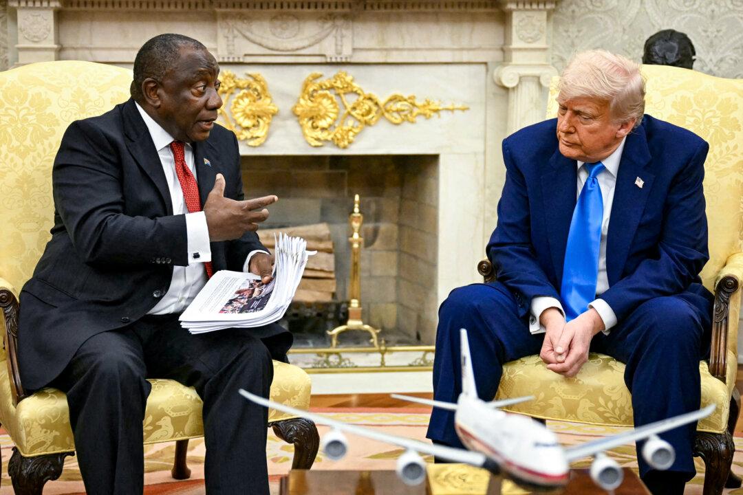 President Donald Trump hands papers to South African President Cyril Ramaphosa during a meeting in the Oval Office of the White House on May 21, 2025. (Jim Watson/AFP via Getty Images)