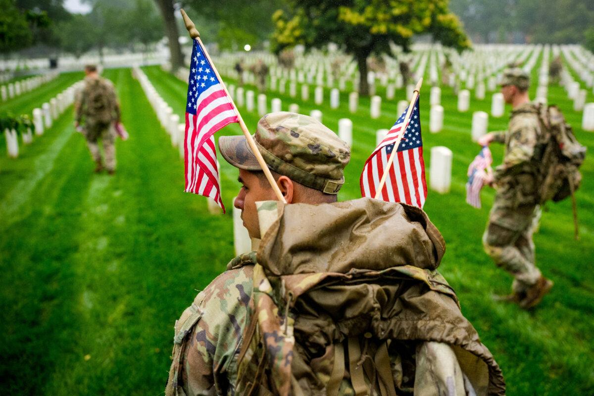 Members of the 3rd U.S. Infantry Regiment place flags at the headstones of U.S. military personnel buried at Arlington National Cemetery, in preparation for Memorial Day in Arlington, Va., on May 22, 2025. Nearly 1,500 service members entered the cemetery at pre-dawn hours to begin the process of placing a flag in front of approximately 260,000 headstones. (Andrew Harnik/Getty Images)