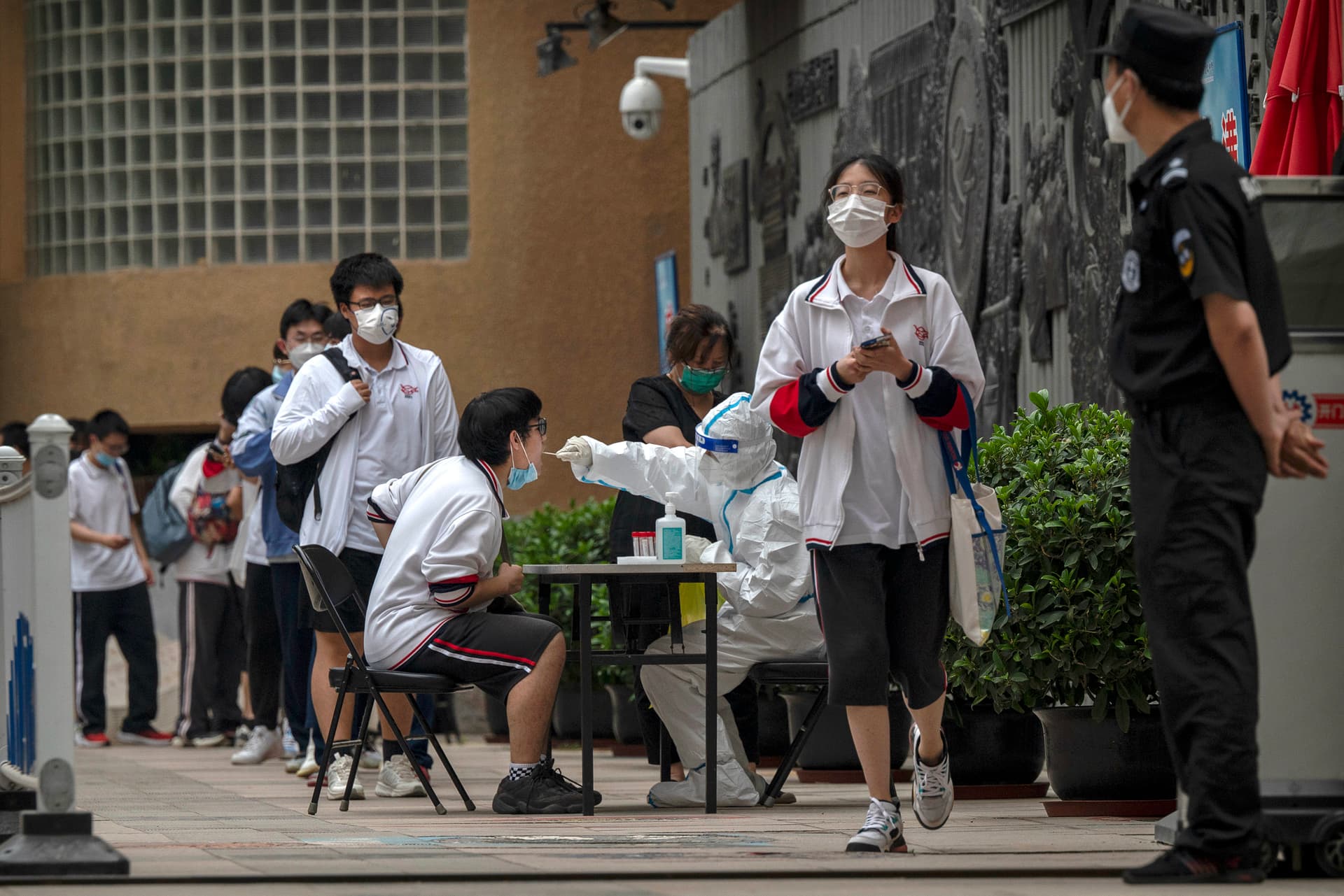 A student is given a nucleic acid test to detect COVID-19 by a health worker in protective clothing in Beijing on June 10, 2022. (Kevin Frayer/Getty Images)