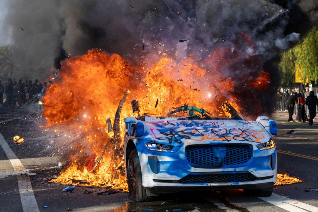 A Waymo vehicle is burning, as protesters clash with law enforcement in the streets surrounding the federal building during a protest following federal immigration operations in Los Angeles on June 8, 2025. (Ringo Chiu/AFP via Getty Images)