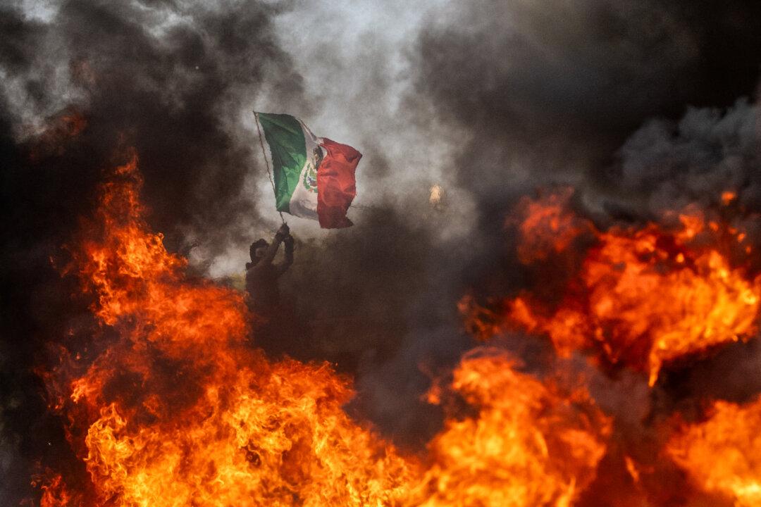 A protester holds up a flag of Mexico amid clashes with law enforcement in the streets surrounding the federal building during a protest following federal immigration operations in Los Angeles on June 8, 2025. (Ringo Chiu/AFP via Getty Images)