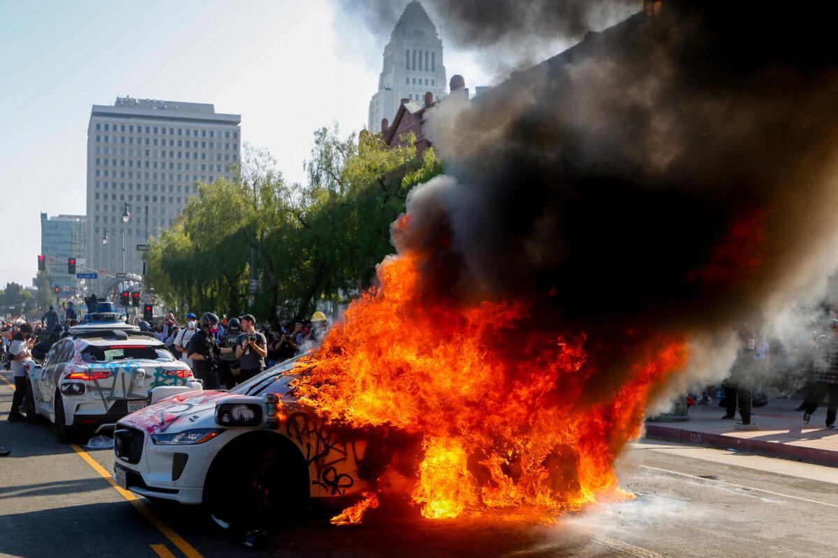 Flames engulf an autonomous Waymo vehicle during an anti-ICE protest in downtown Los Angeles on June 8, 2025. (Benjamin Hanson/Middle East Images/AFP via Getty Images)