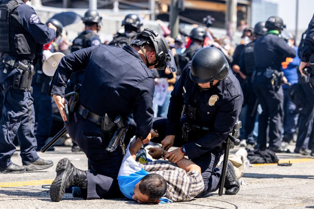 LAPD officers arrest a protester wearing stilts during an anti-ICE protest in downtown Los Angeles on June 8, 2025. (Benjamin Hanson/Middle East Images/AFP via Getty Images)