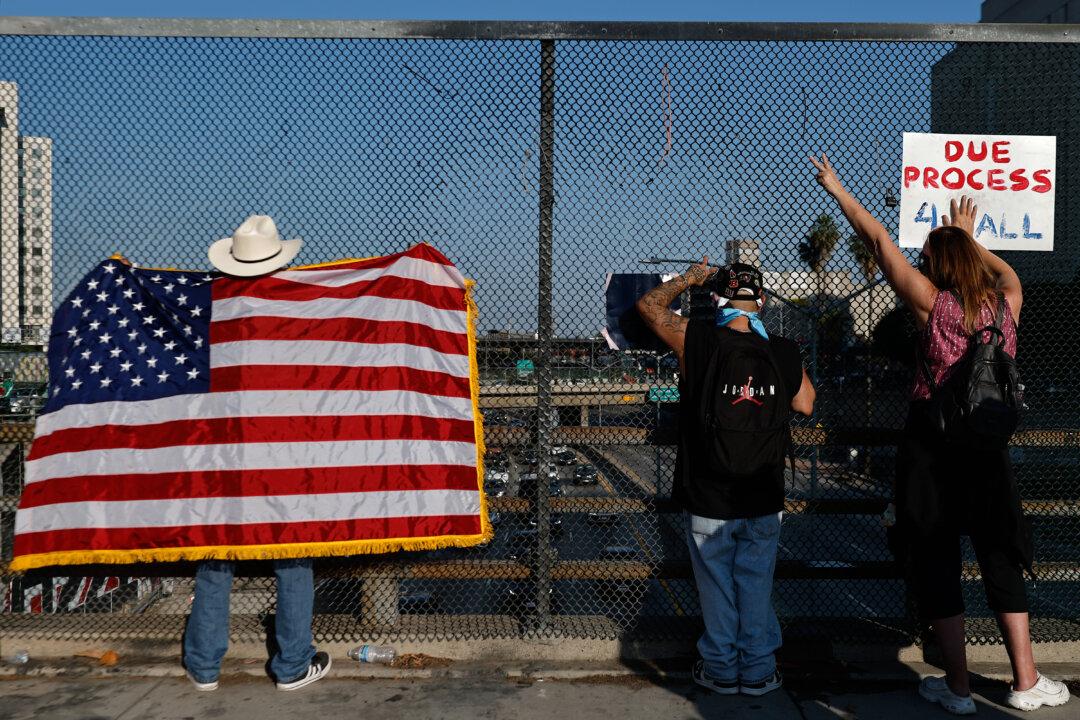 A man holds up an American flag while looking at protesters blocking the 101 freeway in Los Angeles on June 8, 2025. (Mario Tama/Getty Images)