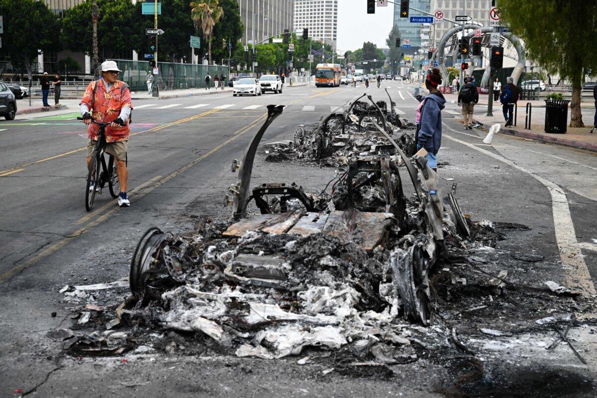 People look at the charred remains of a burned Waymo vehicle in the street following a night of protests in response to federal immigration operations in Los Angeles, on June 9, 2025. (Ronaldo Schemidt/AFP via Getty Images)
