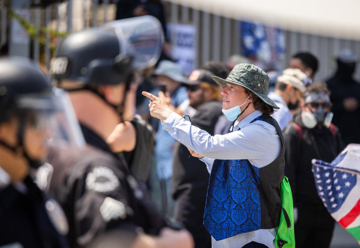 A protester taunts police officers as they block a street leading to a federal facility in downtown Los Angeles on June 9, 2025. (John Fredricks/The Epoch Times)