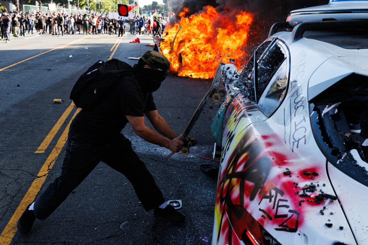 A protester shatters the window of a Waymo vehicle during a demonstration following federal immigration enforcement operations in Los Angeles. Demonstrators torched cars and scuffled with security forces on June 8, 2025, as police kept them away from the National Guard troops sent by President Donald Trump. (Blake Fagan/AFP via Getty Images)