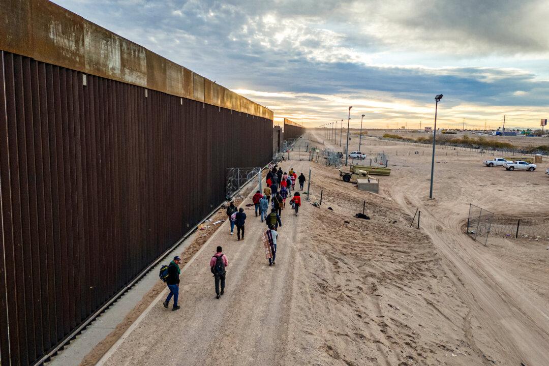 Illegal immigrants walk along the U.S.–Mexico border wall after crossing the Rio Grande into El Paso, Texas, on Feb. 1, 2024. Texas Rangers Staff Captain Troy Wilson told a Senate hearing in May that drone incursions along the Texas–Mexico border are a growing problem. (John Moore/Getty Images)