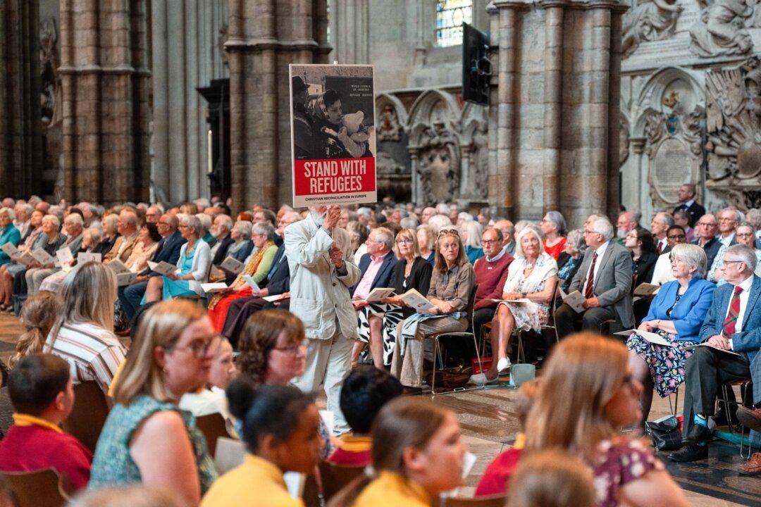 A man carries an old Christian Aid placard during a service of Thanksgiving to mark the 80th anniversary of Christian Aid, at Westminster Abbey in London on June 12, 2025. Christian Aid was founded in 1945 by British and Irish churches to help refugees following World War II. Today it mostly operates as a relief and development charity working to support sustainable development, eradicate poverty, support civil society and provide disaster relief in South America, the Caribbean, Africa and Asia. (Carl Court/Getty Images)