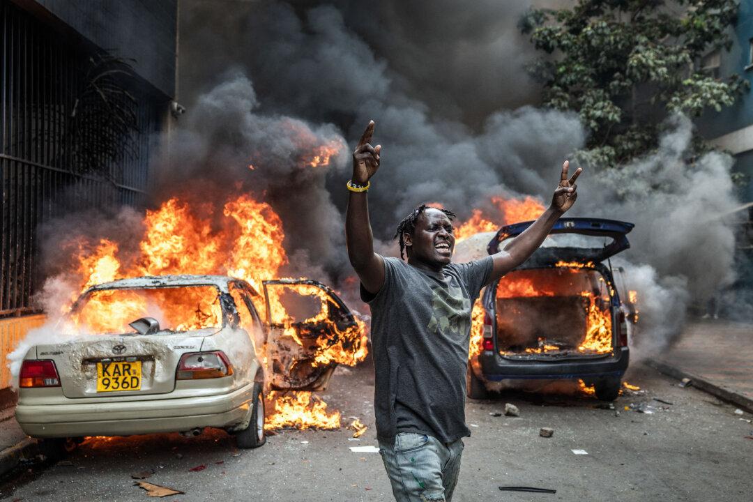 A protester reacts in front of burning cars as clashes erupt between demonstrators and police during a protest over the death of Kenyan blogger Albert Ojwang, who died in police custody, in Nairobi on June 12, 2025. The protests threatened to overshadow the Kenyan government's attempts to pass its 2025-2026 budget without sparking unrest. (Luis Tato/AFP via Getty Images)