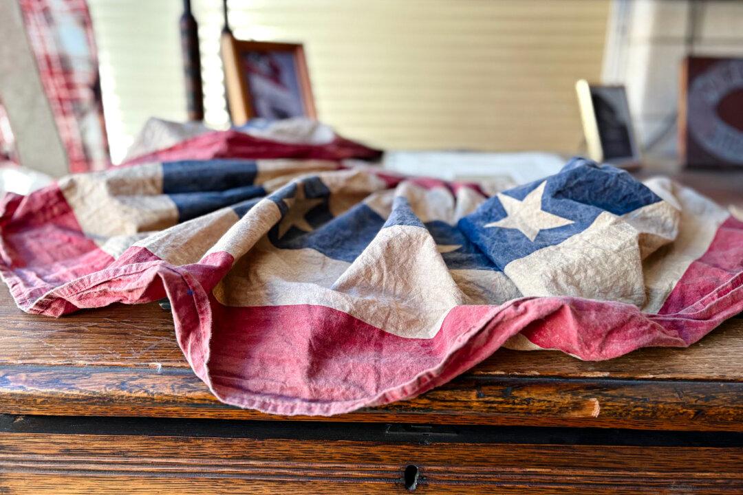 (Top) Artie Schaller III in front of a cabinet of mementos from the National Flag Company's history in Cincinnati on June 6, 2025. (Bottom) A red, white, and blue bunting at the National Flag Company in Cincinnati on June 6, 2025. (Nathan Worcester/The Epoch Times)
