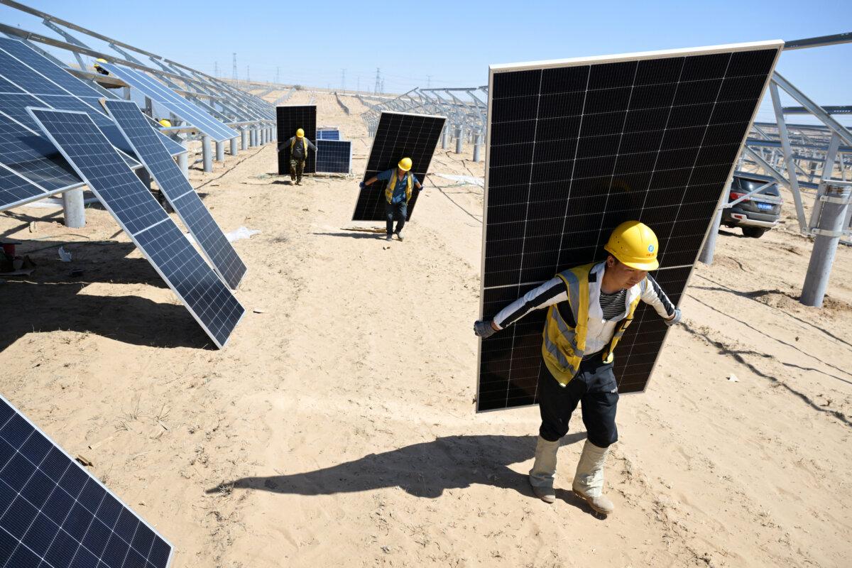 Workers carry solar panels to be installed in the desert at the Ningguoyun Lingwu 1 million kilowatt photovoltaic project in Lingwu, Ningxia region, China, on April 14, 2025. (AFP via Getty Images)