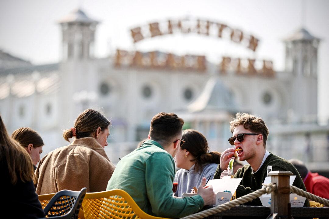 Customers eat lunch overlooking the Palace Pier, outside Captain's Fish and Chips shop in Brighton, England, on March 25, 2022. (Adrian Dennis/AFP via Getty Images)