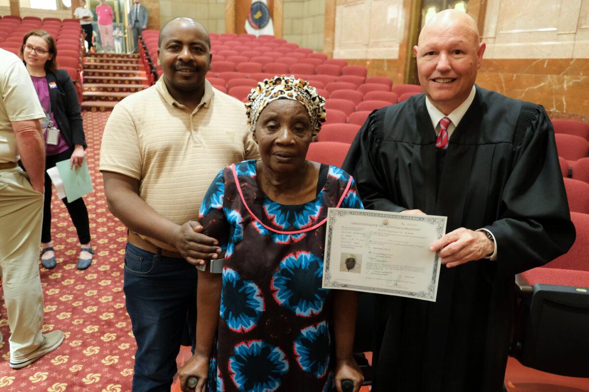 U.S. District Court Judge James R. Sweeney II (R) presents a certificate of naturalization to a new citizen at the Indiana War Memorial in Indianapolis on June 26, 2025. (Lawrence Wilson/The Epoch Times)