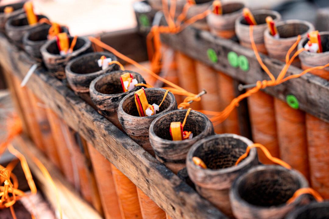 (Top) Workers place fireworks on mortars for a show by Rozzi’s Famous Fireworks along the Ohio River in Ludlow, Ky., on June 27, 2025. (Bottom) Fireworks are placed in mortars on a barge for a show along the Ohio River in Ludlow, Ky., on June 27, 2025. (Samira Bouaou/The Epoch Times)