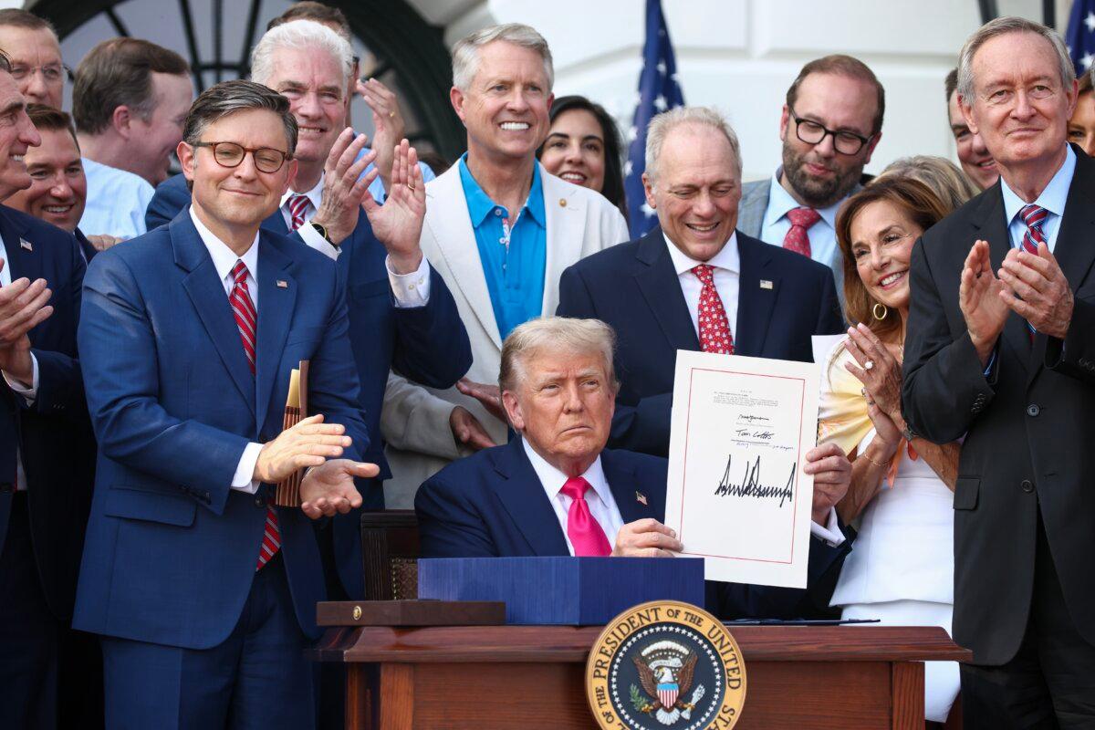 President Donald Trump, joined by Republican lawmakers, signs the One Big Beautiful Bill Act into law during an Independence Day military family picnic on the South Lawn of the White House on July 4, 2025. (Samuel Corum/Getty Images)