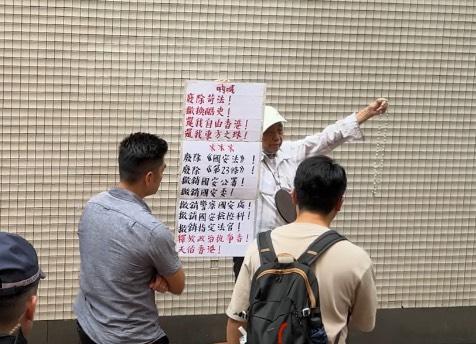 A man holds a sign in Causeway Bay demanding the repeal of the national security law, in Hong Kong, on July 1, 2025. (Ruilue Wu/The Epoch Times)