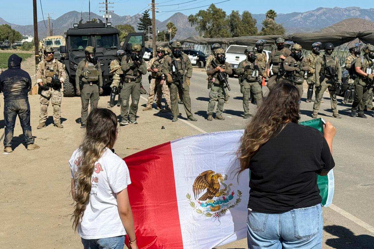 Demonstrators hold a Mexican flag in front of federal agents blocking a road during an immigration operation in Camarillo, Calif. (Michael Owen Baker/AP Photo)