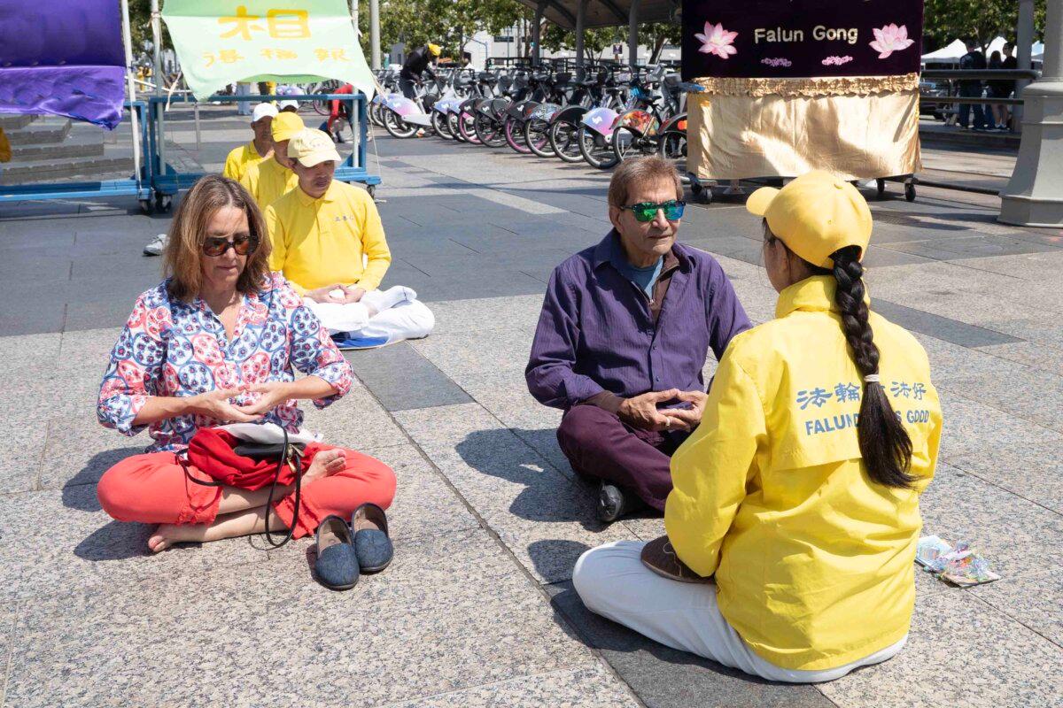 Sam (2nd R) learns the fifth Falun Gong exercise in Harry Bridges Plaza in San Francisco on July 12, 2025. (Gary Wang/The Epoch Times)