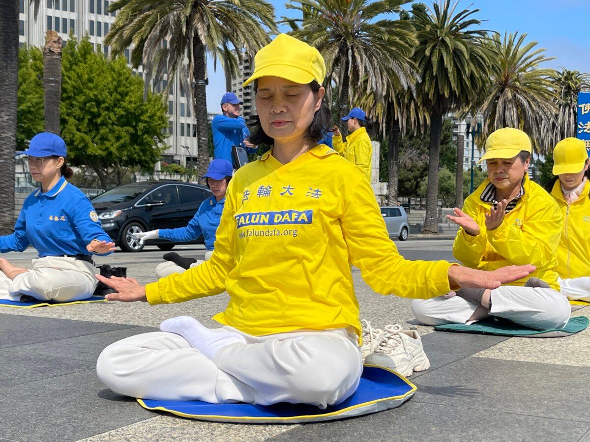 Falun Gong practitioner Yaoxu Liu, a torture survivor, meditates in Harry Bridges Plaza on July 12, 2025. (Belinda Yu/The Epoch Times)
