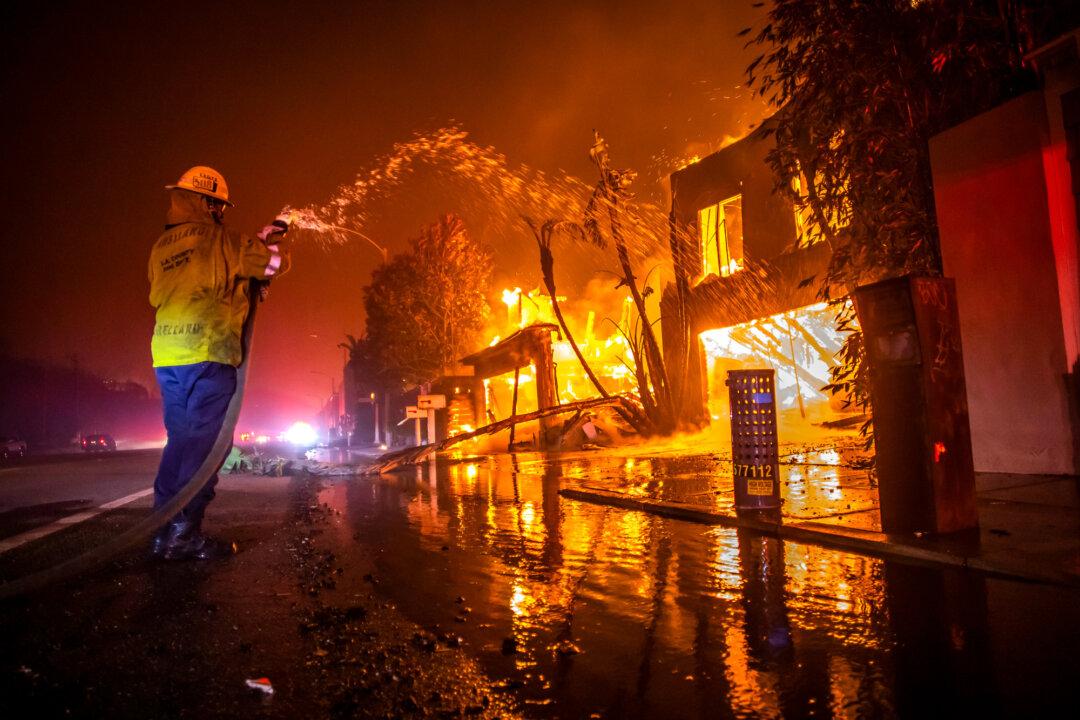 A firefighter battles the Palisades Fire as it burns homes on the Pacific Coast Highway during a powerful windstorm in Los Angeles on Jan. 8, 2025. The wildfire lasted for 24 days, resulting in the deaths of 12 residents, forced thousands to evacuate their homes, and rendered entire neighborhoods uninhabitable. (Apu Gomes/Getty Images)