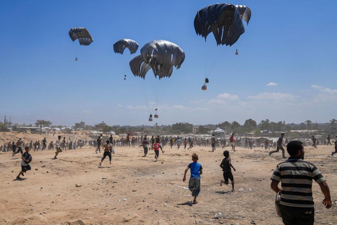 Palestinians rush to collect humanitarian aid airdropped by parachute into Zawaida in the central Gaza Strip, on Aug. 4, 2025. (Abdel Kareem Hana/AP Photo)