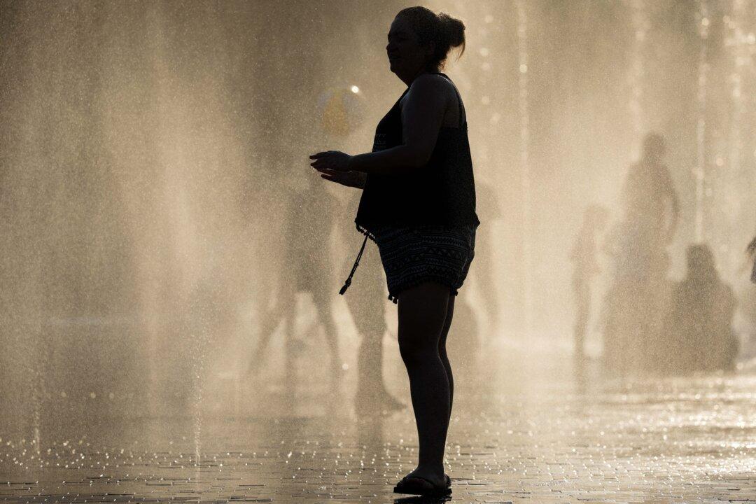 People seek relief under water jets at a splash pad in the Madrid Rio park during a heatwave in Madrid, on Aug. 4, 2025. (Pierre-Philippe Marcou/AFP via Getty Images)