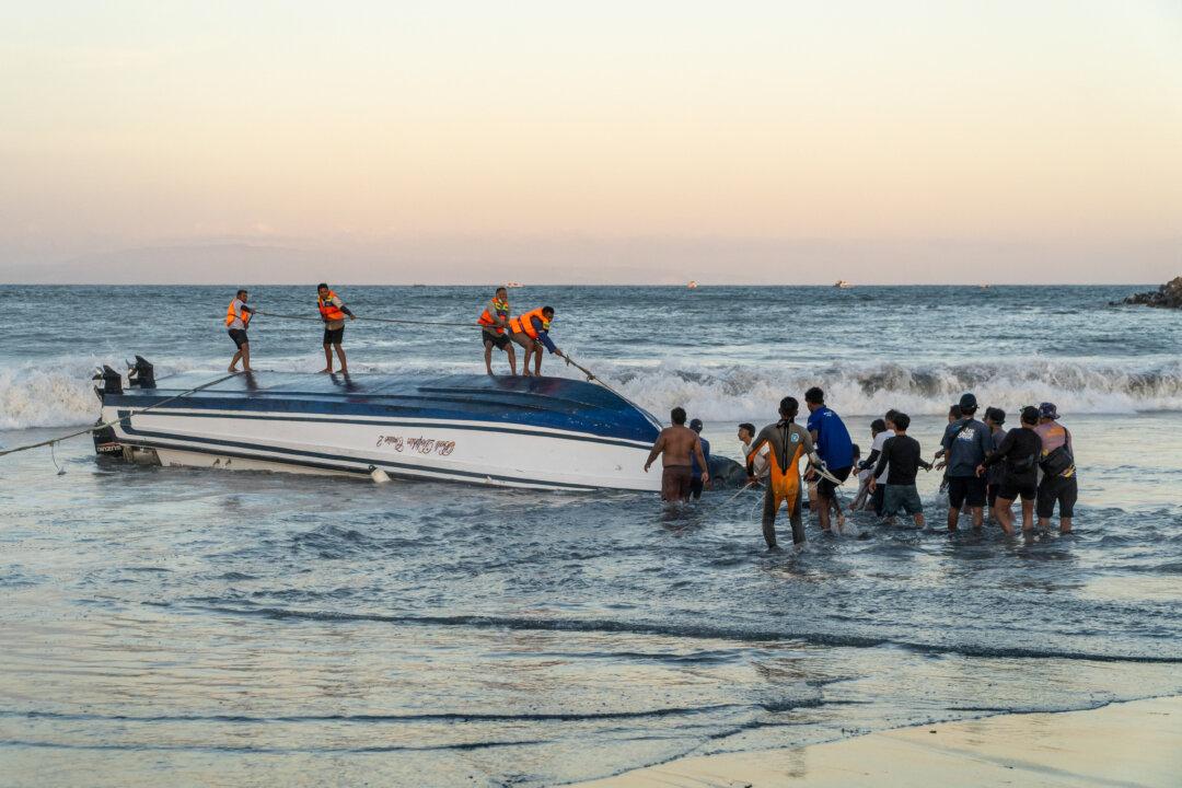 Locals and rescue workers attempt to recover an overturned speedboat after it sank near Sanur port in Bali, on Aug. 5, 2025. Two Chinese nationals were killed and an Indonesian was missing after the boat sailing to the popular island of Bali with dozens onboard sank and ran aground, rescue authorities said. (Dicky Bisinglasi/AFP via Getty Images)