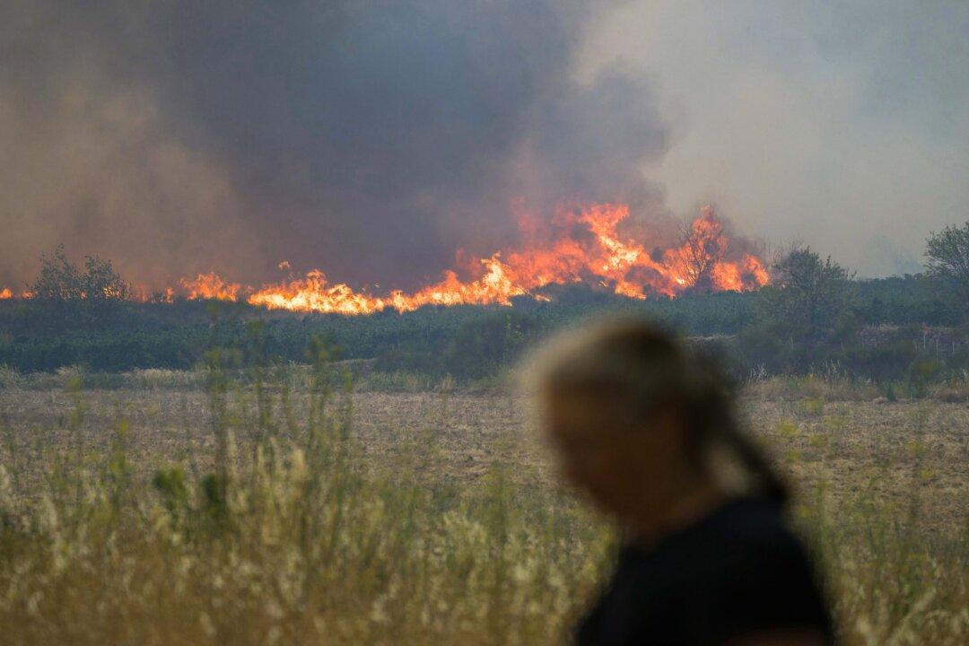 A resident walks as smoke billows from a forest fire in Tournissan, France, on Aug. 5, 2025. A fire that broke out in the afternoon in Ribaute (Aude) had already spread across 1,000 hectares (2471 acres) by early evening, according to the prefecture, prompting the evacuation of at least one campsite and several homes, an AFP journalist reported. (Idriss Bigou-Gilles/AFP via Getty Images)