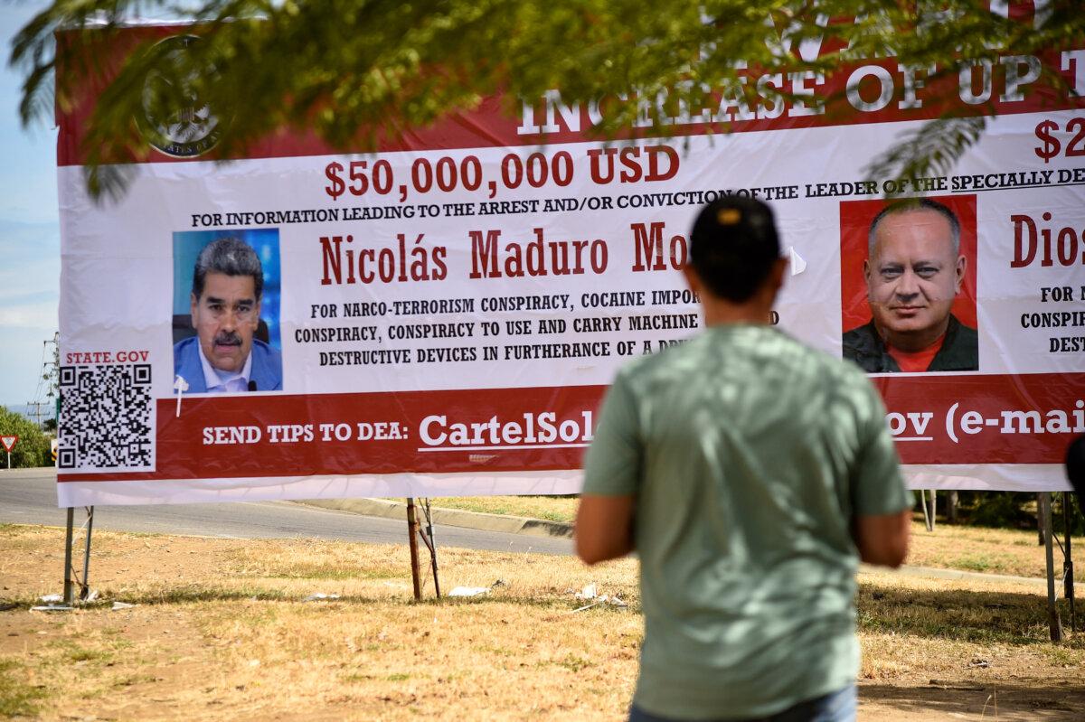A man looks at a banner offering a reward for information leading to the arrest of Venezuelan President Nicolás Maduro and Venezuelan Minister of Interior Relations, Justice, and Peace Diosdado Cabello, in Villa del Rosario, Colombia, on Aug. 23, 2025. (Schneyder Mendoza/AFP via Getty Images)