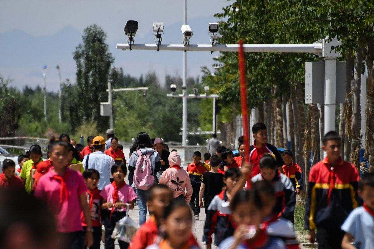 Schoolchildren walk below surveillance cameras in Akto, in China's western Xinjiang region, on June 4, 2019. (Greg Baker/AFP via Getty Images)