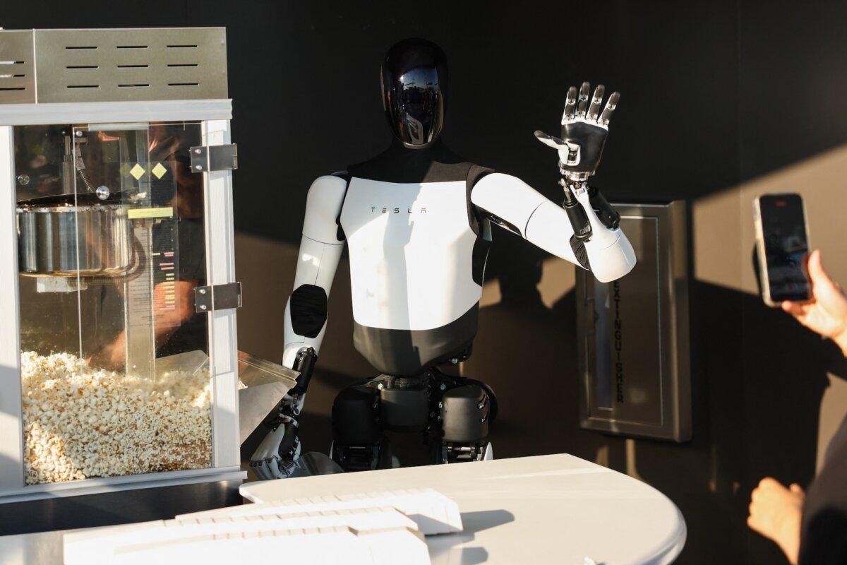 A Tesla Optimus robot scoops popcorn and waves at attendees at the Tesla Diner and Drive-In restaurant and Supercharger in Los Angeles, Calif., on July 21, 2025. (Patrick T. Fallon/AFP/Getty Images)