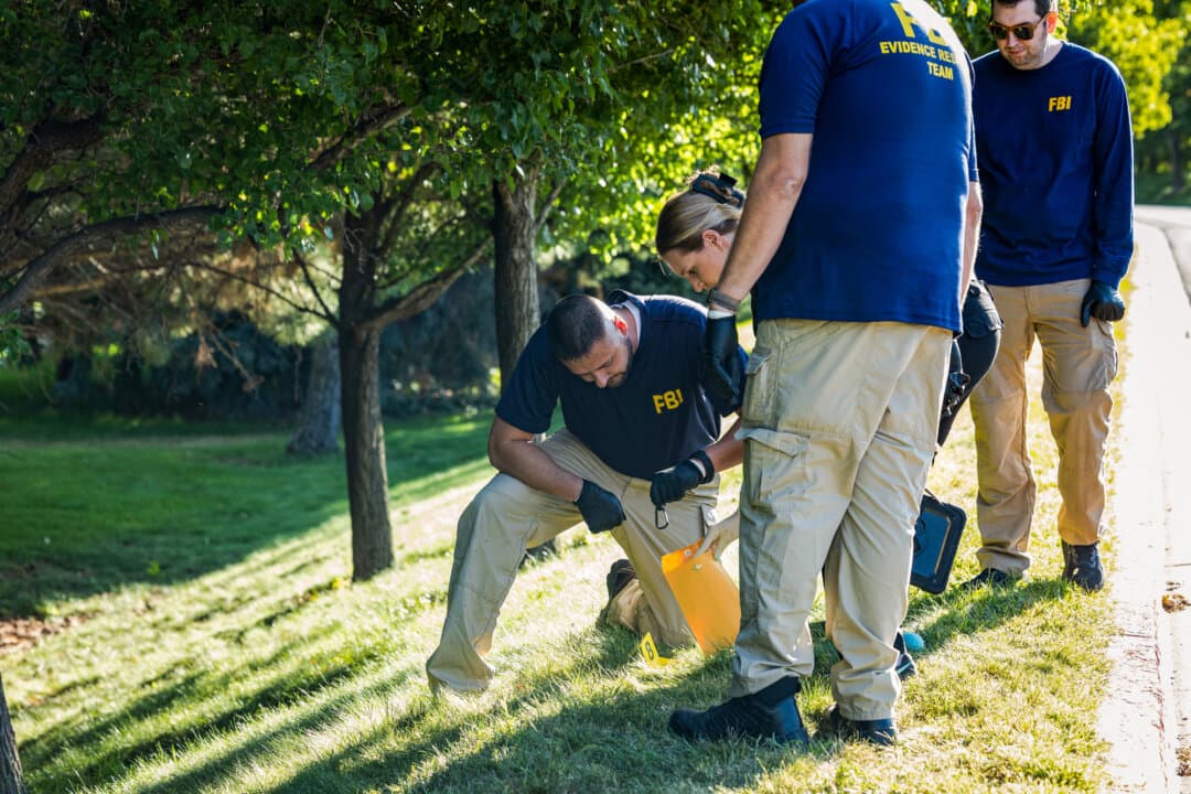 Law enforcement officials, including members of an FBI forensics team, investigate near the crime scene where Charlie Kirk was shot and killed at Utah Valley University in Orem, Utah, on Sept. 11, 2025. (Melissa Majchrzak/AFP via Getty Images)