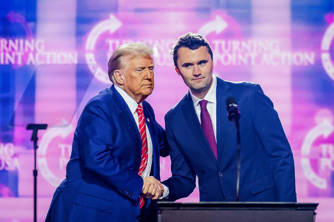 Conservative influencer Charlie Kirk (R) shakes hands with President Donald Trump as he speaks on the stage at AmericaFest 2024 in Phoenix on Dec. 22, 2024. (Josh Edelson/AFP via Getty Images)