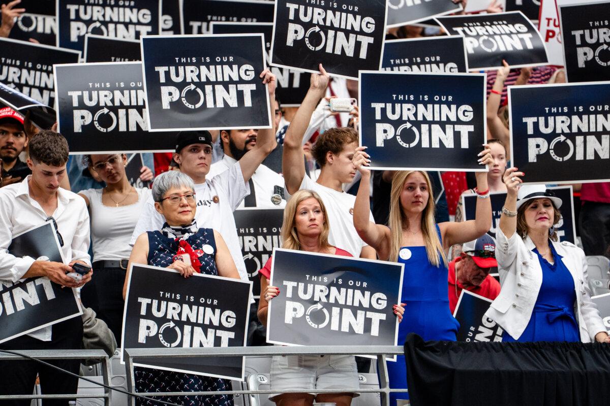 People hold signs as they take part in the Building a Legacy: Remembering Charlie Kirk Memorial event at the State Farm Stadium in Glendale, Ariz., on Sept. 21, 2025. (Madalina Kilroy/The Epoch Times)