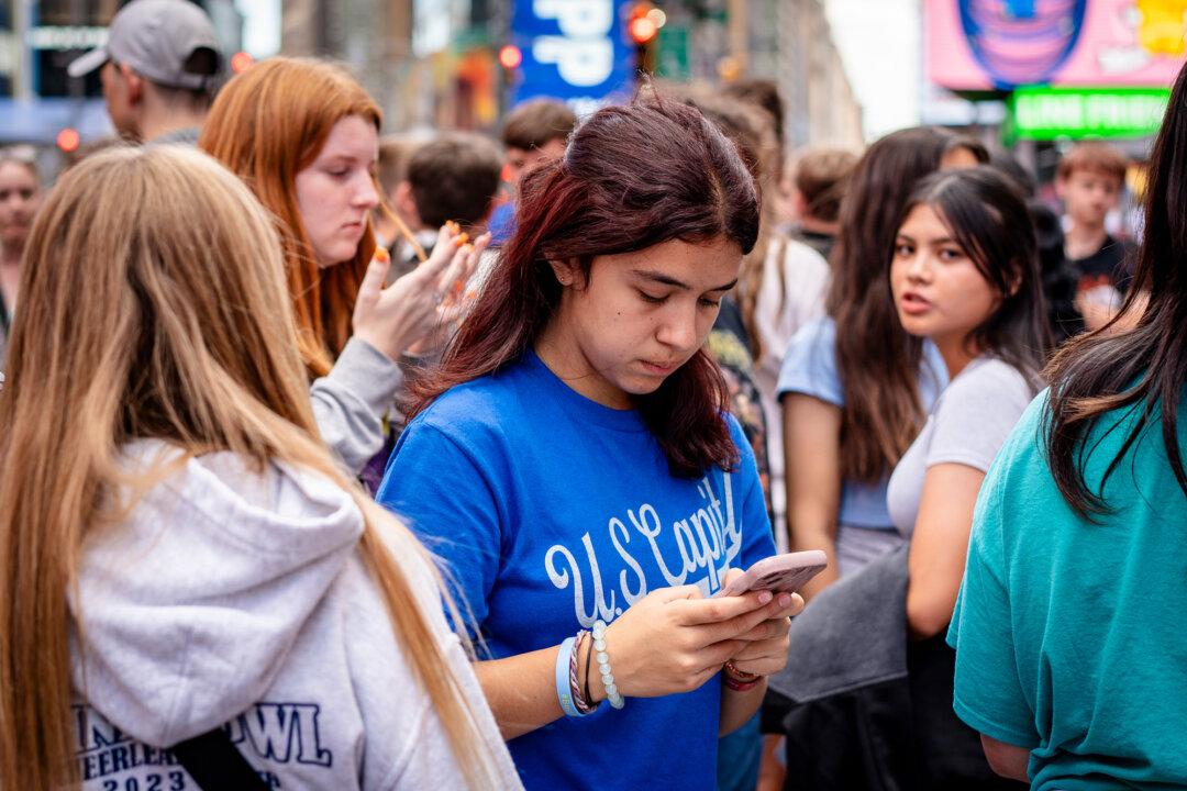 A young woman uses a cell phone in New York City on June 10, 2024. Experts warn that the flood of violent imagery on social media is distorting people’s attitudes toward violence. (Samira Bouaou/The Epoch Times)
