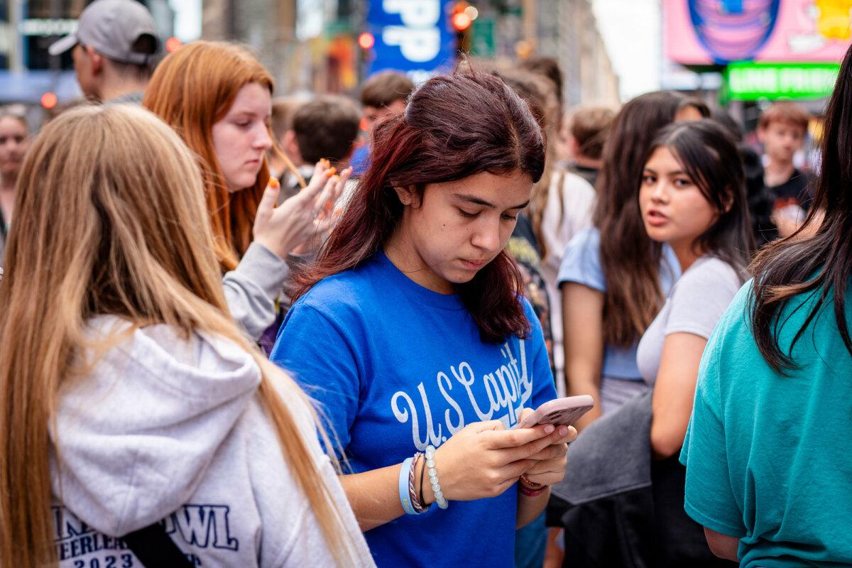 A young woman uses a cellphone in New York City on June 10, 2024. Experts warn that social media is distorting young people's view of the world. (Samira Bouaou/The Epoch Times)