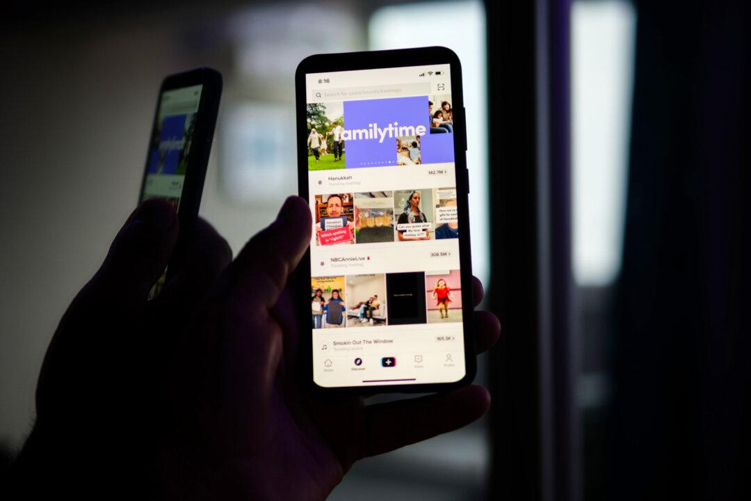 A man holds a phone displaying the TikTok app in a file photo on Aug. 11, 2024. A 2024 survey of teens in England and Wales found that 44 percent of TikTok users reported seeing violent content in the past year. (Oleksii Pydsosonnii/The Epoch Times)