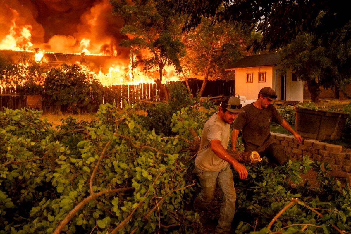 Layne Smith (L) clears vegetation to stop flames from spreading to his home as the 6-5 fire burns through the Chinese Camp community in Tuolumne County, Calif., on Sept. 2, 2025. (Noah Berger/AP Photo)