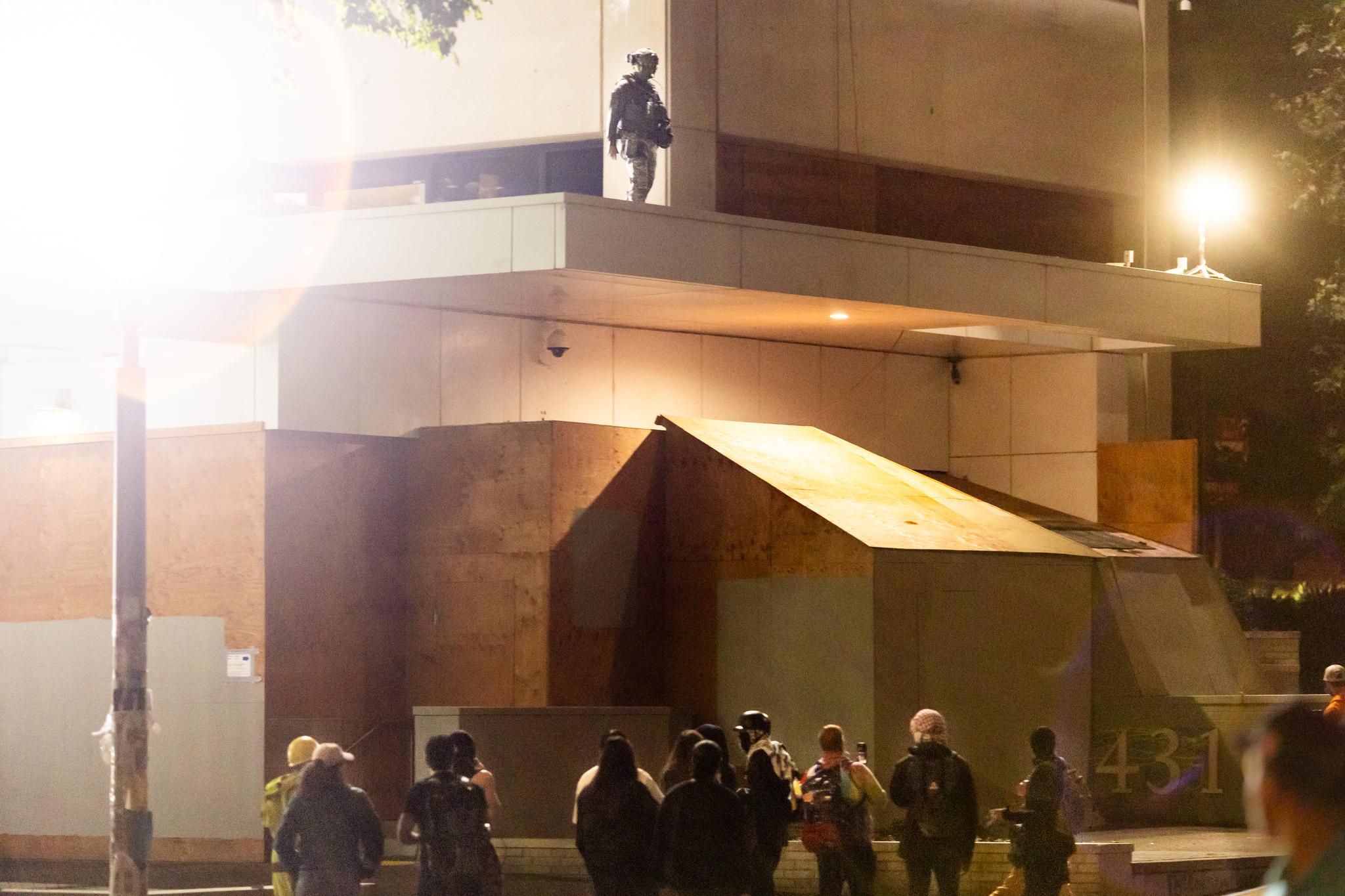 Federal agents shine bright lights as protesters stand in front of Immigration and Customs Enforcement offices in Portland, Ore., on Oct. 3, 2025. (John Fredricks/The Epoch Times)