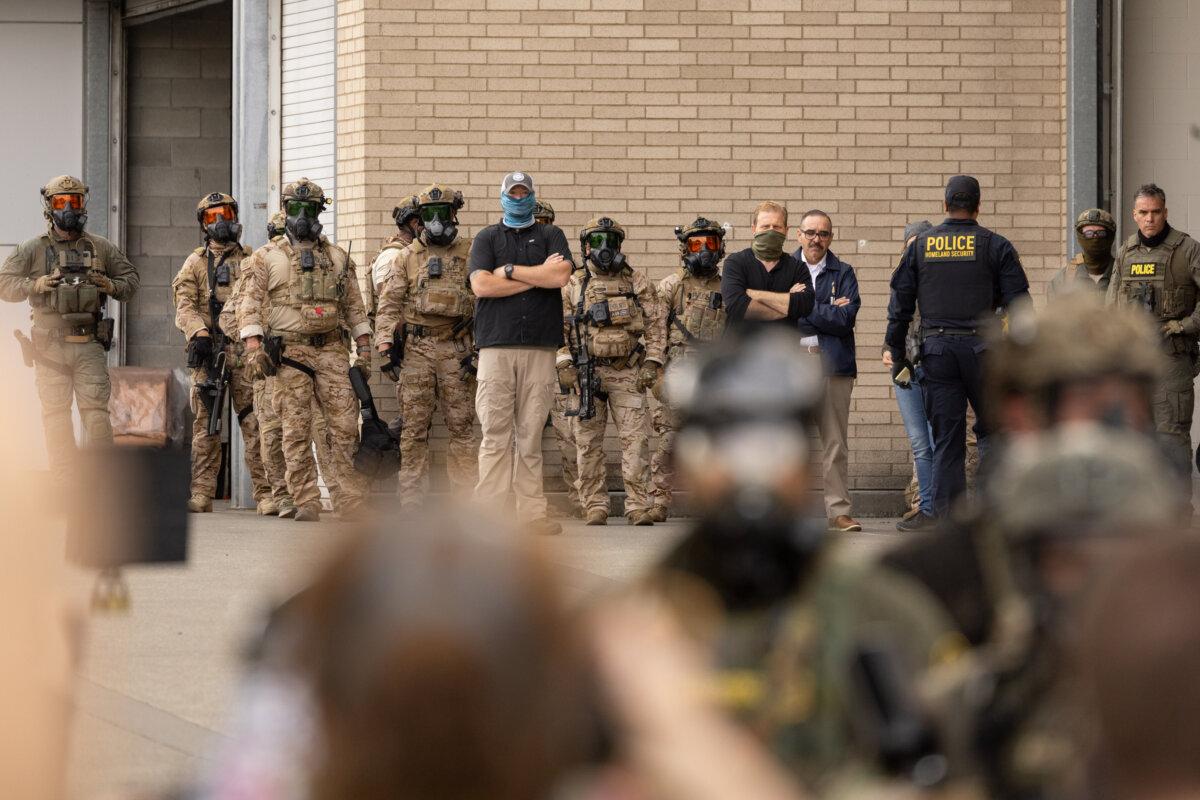 Federal agents monitor protesters standing in front of Immigration and Customs Enforcement offices in Portland, Ore., on Oct. 4, 2025. (John Fredricks/The Epoch Times)