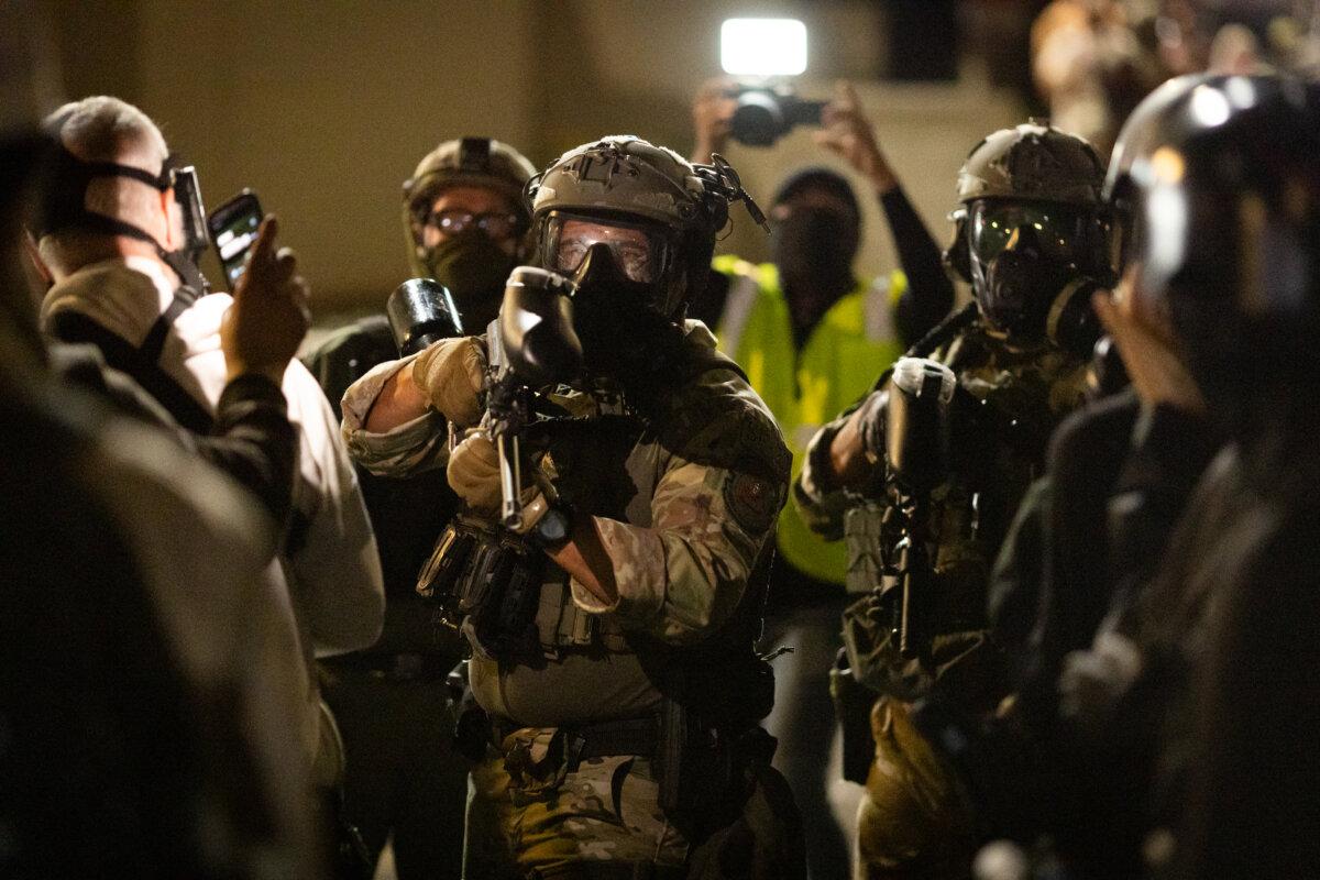 A federal agent prepares to fire pepper ball rounds at protesters in front of Immigration and Customs Enforcement offices in Portland, Ore., on Oct. 4, 2025. (John Fredricks/The Epoch Times)