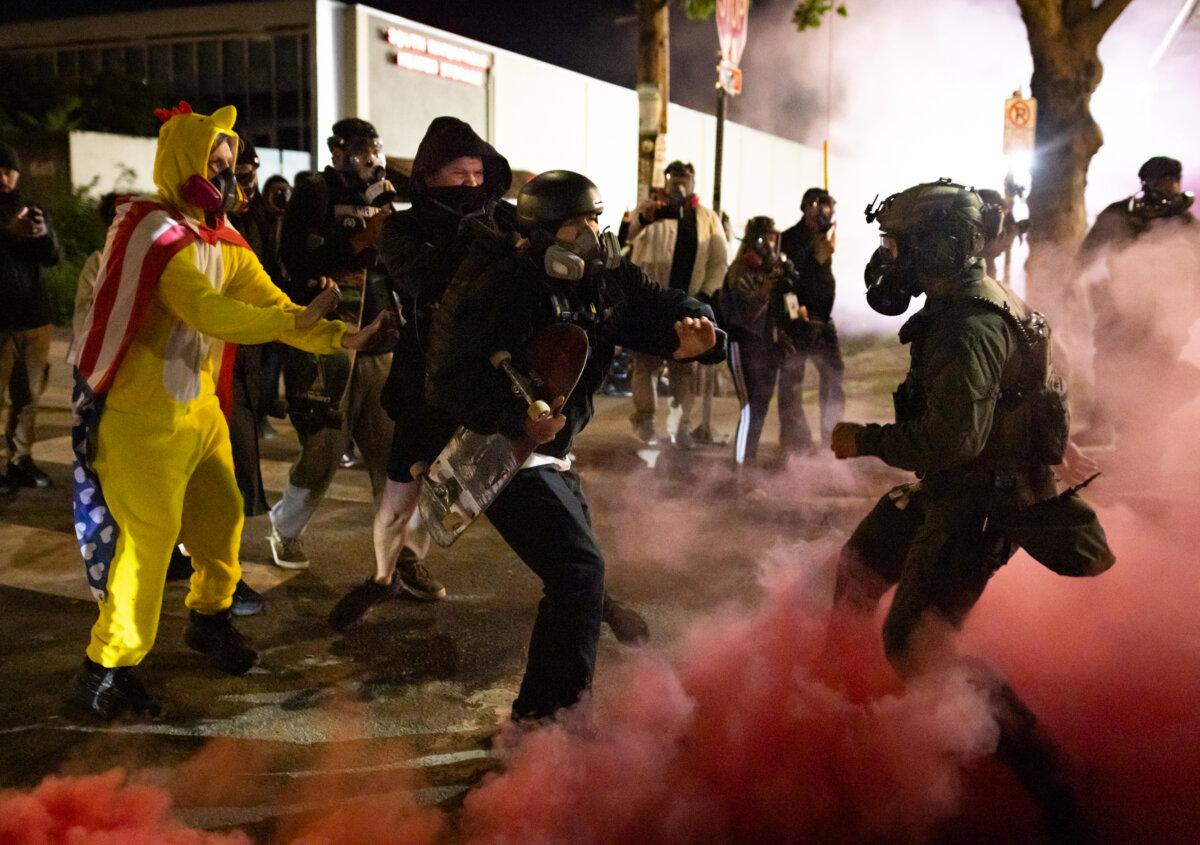 An Antifa protester kicks a smoke bomb back at federal officers in front of Immigration and Customs Enforcement offices in Portland, Ore., on Oct. 5, 2025. (John Fredricks/The Epoch Times)