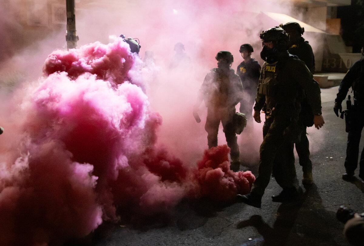Federal officers deploy smoke grenades to deter protesters at Immigration and Customs Enforcement offices in Portland, Ore., on Oct. 5, 2025. (John Fredricks/The Epoch Times)