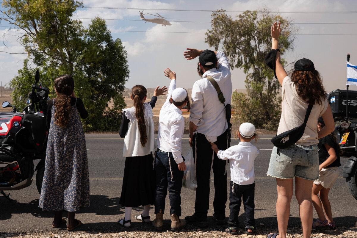 Israelis gather with national flags outside the Reim military base near the border with Gaza in southern Israel to welcome the hostages about to arrive following their release by Hamas from the Gaza Strip on Oct. 13, 2025. (MAYA LEVIN/AFP via Getty Images)