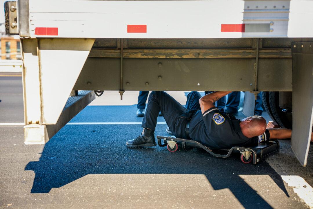 A police officer looks under a truck at a traffic-safety checkpoint in Washington on Sept. 8, 2025. A nationwide audit by the Federal Motor Carrier Safety Administration of non-domiciled commercial driver’s licenses found widespread noncompliance in several states, with California showing the most serious problems in how it issued such licenses. (Andrew Harnik/Getty Images)