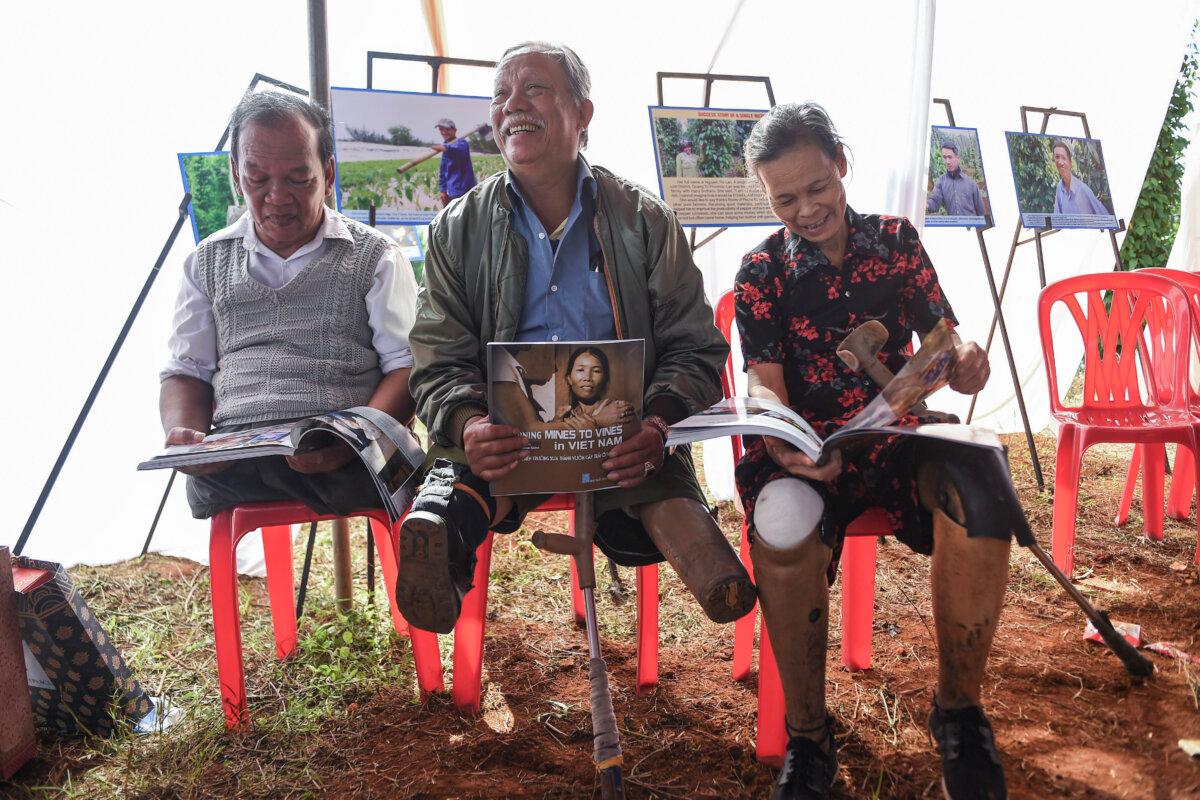 Landmine victims Phan Van Ty (L), Truong Uu (C), and Hoang Thi Luu (R) read books about farmers who became landmine victims, on Jan. 6, 2020. (Nhac Nguyen/AFP via Getty Images)
