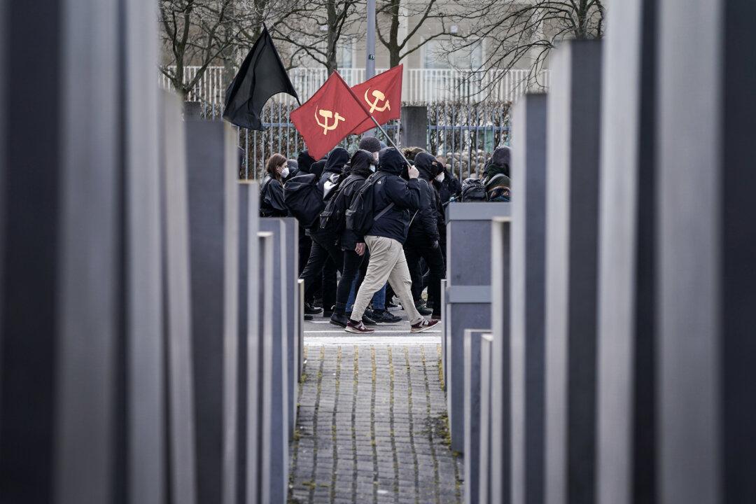Antifa protesters carrying communist flags march past the Holocaust Memorial while demonstrating against gatherings of neo-Nazis nearby in the city center in Berlin on March 20, 2021. (Sean Gallup/Getty Images)